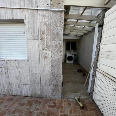 קיר עם סדק, מטאטא על הרצפה, מכונת כביסה ברקע