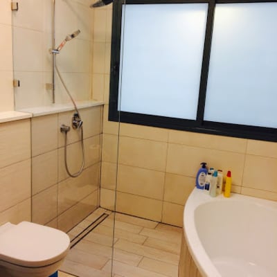 חדר אמבטיה עם מקלחון זכוכית ושירותים