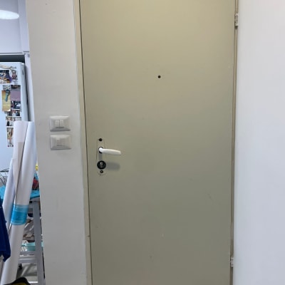 דלת מתכת עם ידית לבנה ומנעול