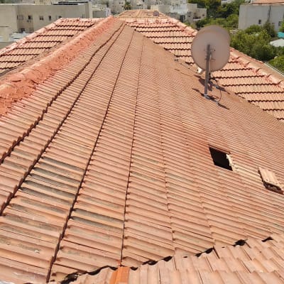 גג רעפים עם אנטנה ואדם עובד על תיקון