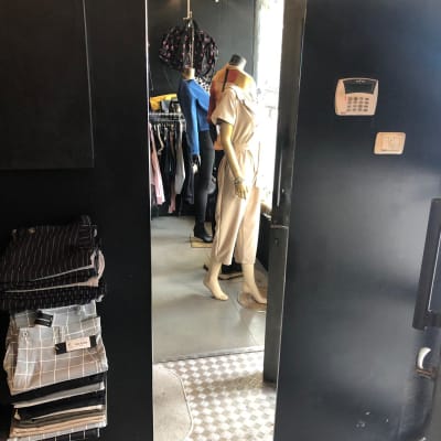 בובת תצוגה משתקפת במראה זכוכית בחנות בגדים