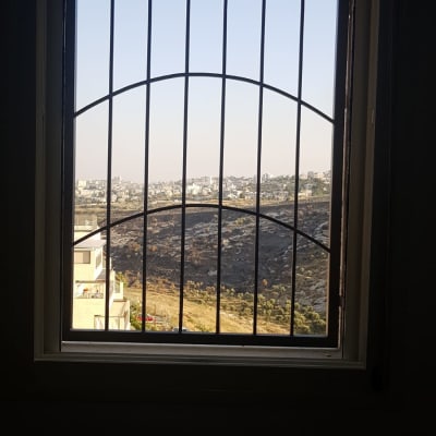 חלון עם סורגים מתכתיים ונוף חיצוני