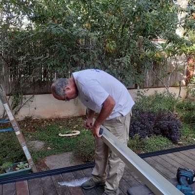 אדם עובד עם פרופיל אלומיניום על רצפת עץ