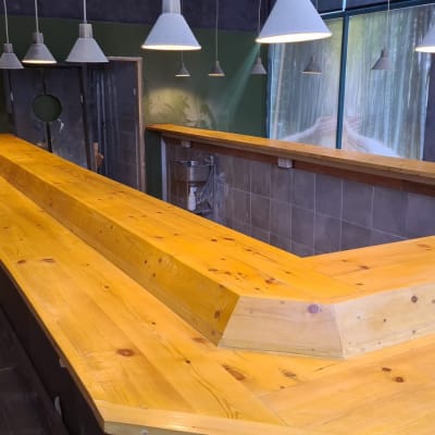 דלפק עץ חדש עם מנורות תלויות בחלל בשיפוץ