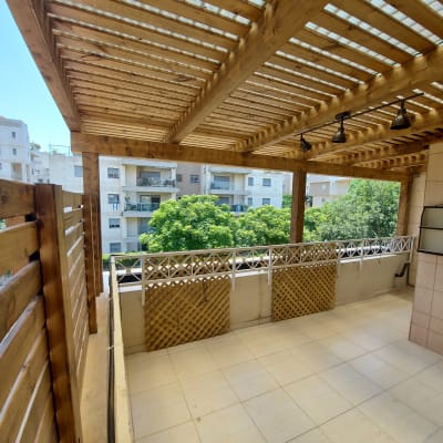 פרגולה מעץ עם תאורה במרפסת מרוצפת