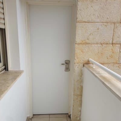 דלת לבנה עם ידית מתכת במרפסת