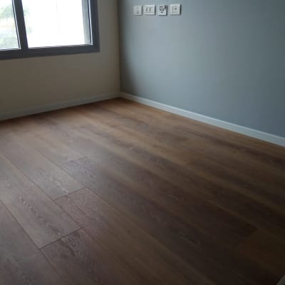 רצפת פרקט עץ כהה בחדר ריק עם חלון