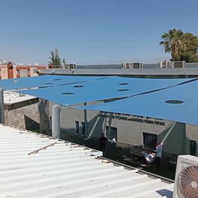 התקנת סוכך כחול על גג עם אנשים ברקע
