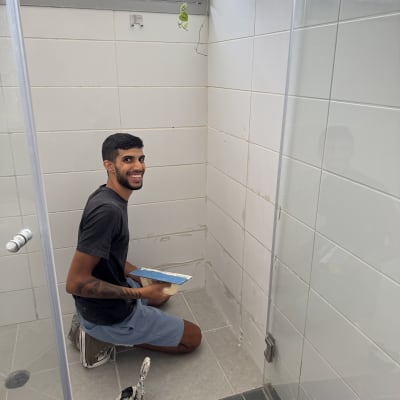 אדם עובד על תיקון אריחים בחדר אמבטיה