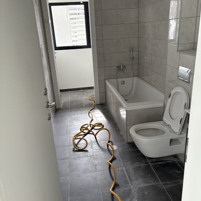 חדר אמבטיה עם צינור על הרצפה, שירותים ואמבטיה