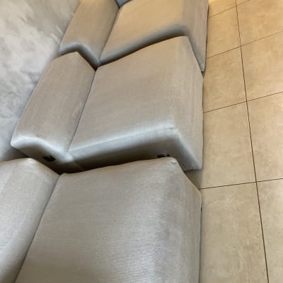 כריות וחלקי ספת בד אפורה נקיים ועומדים לצד הקיר