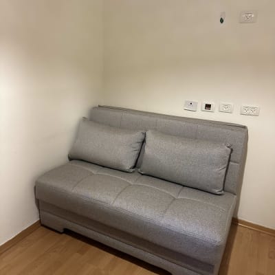 ספה אפורה בחדר עם רצפת עץ