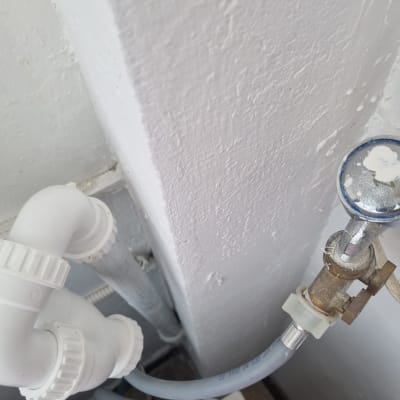 צינורות פלסטיק ולחץ מים ליד קיר צבוע