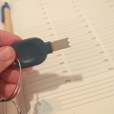 מפתח עם ידית כחולה מוחזק מעל יומן פתוח