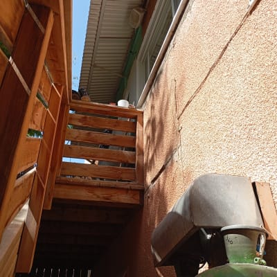 צילינדרים ירוקים ומבנה עץ ליד קיר חיצוני