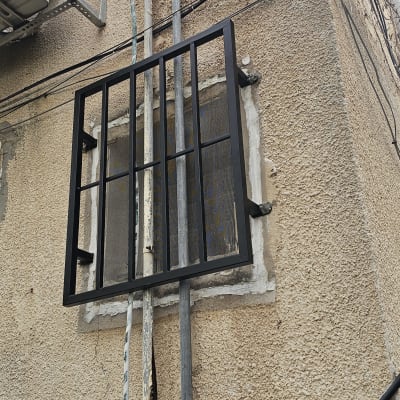 סורג מתכת מותקן על חלון קיר חיצוני