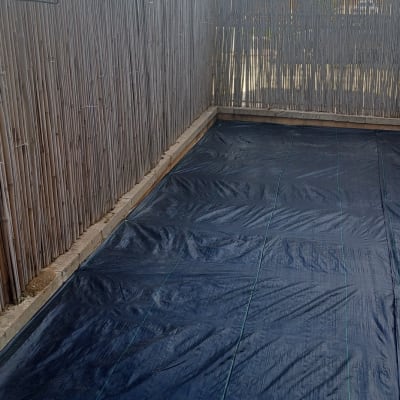 יריעת פלסטיק שחורה על הקרקע בגינה מגודרת