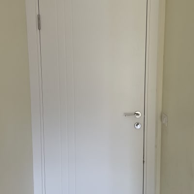 דלת לבנה עם ידית מתכת כסופה וקיר בהיר