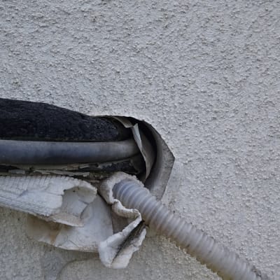 צינור גומי ופלסטיק יוצאים מקיר עם חור