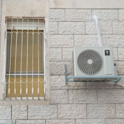 יחידת מיזוג אוויר מותקנת על קיר חיצוני ליד חלון.