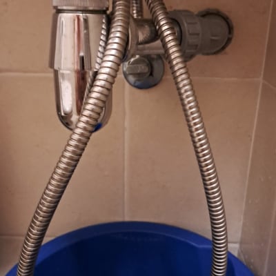 צינור מתכת גמיש מתחת לכיור עם דלי כחול