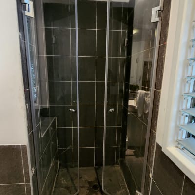 מקלחון עם דלתות זכוכית ורצפת אריחים כהה