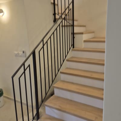 מעקה מתכת על גרם מדרגות עץ בבית