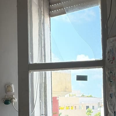 חלון עם זכוכית שבורה ונוף חיצוני