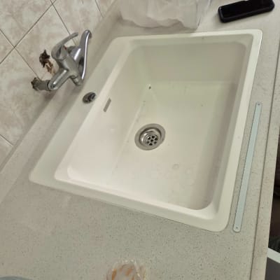 כיור מטבח לבן מותקן במשטח עבודה עם ברז בקיר