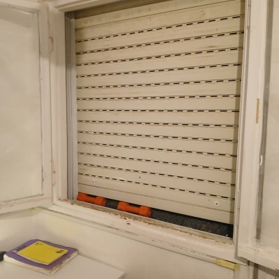 תריס גלילה לבן פתוח חלקית בחלון