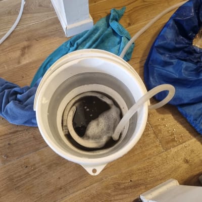 דלי עם צינור ומים על רצפה מעץ