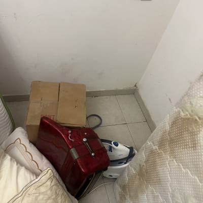 קופסאות, כריות ומגהץ על רצפה ליד קיר