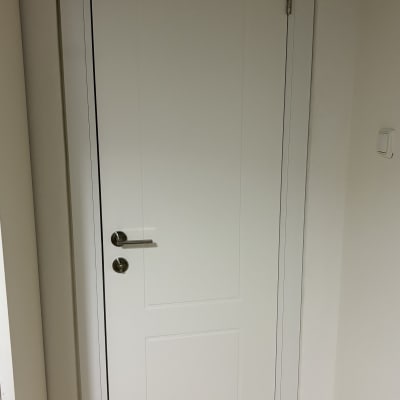 דלת לבנה עם ידית מתכת על רקע קיר לבן