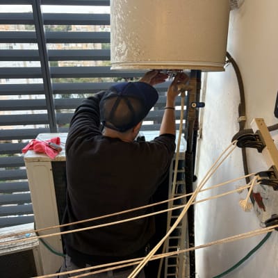 אדם עובד על דוד שמש במרפסת