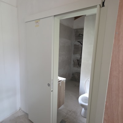 דלת הזזה לבנה בחדר אמבטיה עם שירותים ומקלחת