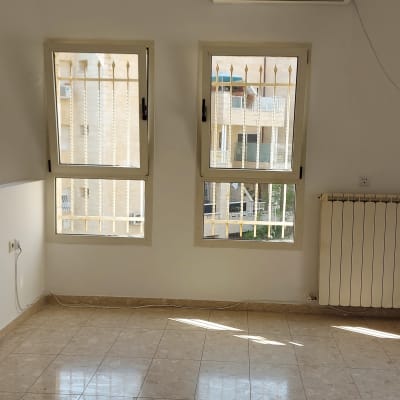 קיר לבן עם חלונות וסורגי מתכת