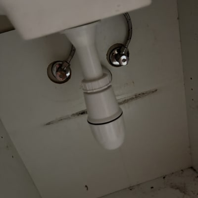 צנרת מתחת לכיור עם סימני דליפה