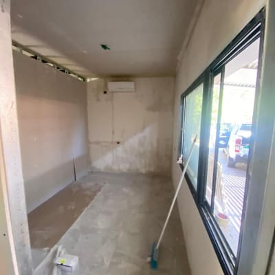 חדר בבנייה עם מטאטא על הרצפה וחלון גדול