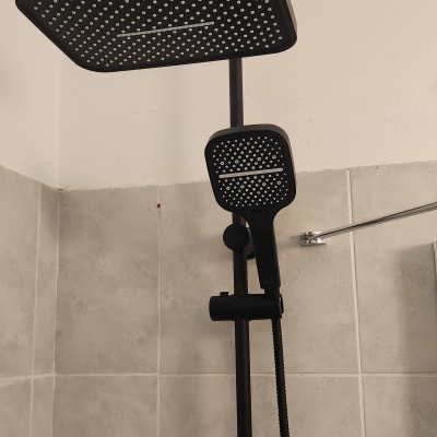 ראש מקלחת שחור על קיר אריחים אפור