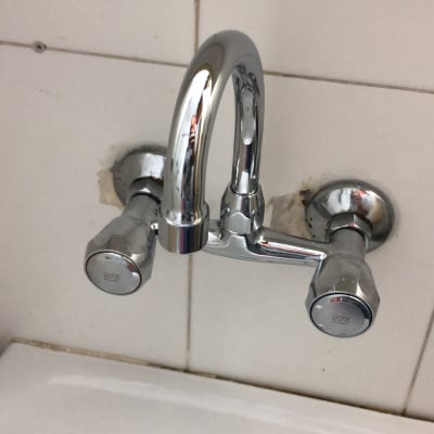 ברז כרום עם ידיות על קיר אריחים