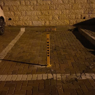 עמוד חניה עם שלט אזהרה על מדרכה בלילה