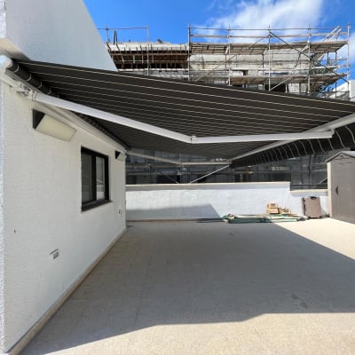 סוכך בד שחור מפוספס מותקן על קיר חיצוני