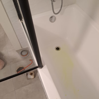 אמבטיה עם סימני נזילה וכלי עבודה על הרצפה