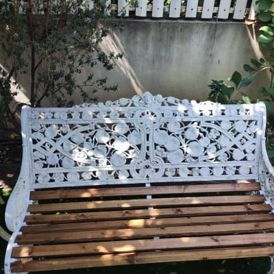 ספסל עץ ומתכת בגינה עם צמחייה מסביב