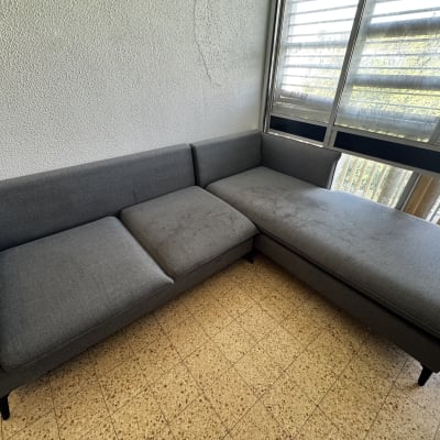 ספה אפורה עם כתמים ליד חלון