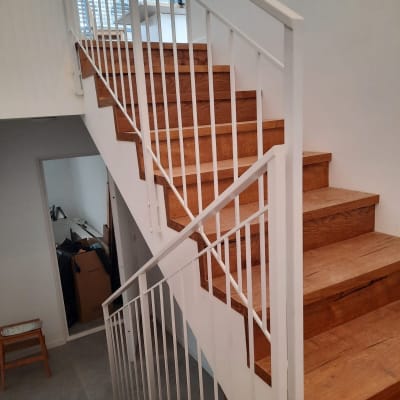 מעקה מתכת לבן על מדרגות עץ בבית