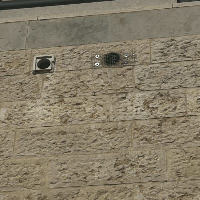 קיר אבן עם פתחי אוורור ורשת מתכת
