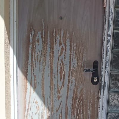 דלת עץ עם צבע מתקלף ומנעול שחור