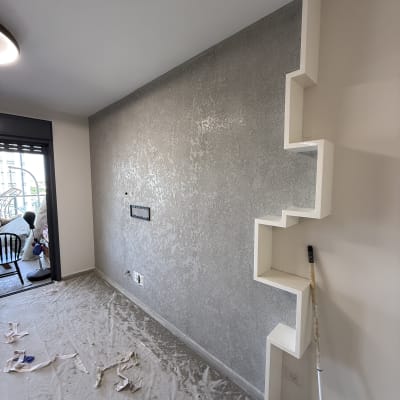 קיר צבוע עם מדף דקורטיבי וכלי עבודה על הרצפה