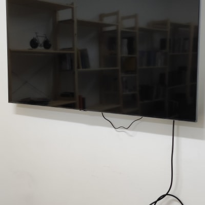 טלוויזיה תלויה על הקיר עם כבל חשמל משתלשל